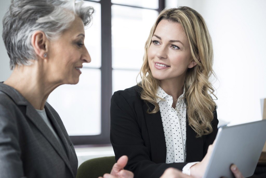 Stereotypical image of an older woman and younger woman in a business environment